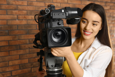Operator with professional video camera near brick wall