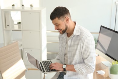 Freelancer working on laptop near table indoors