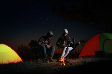 Couple near bonfire at night. Camping season