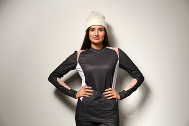 Woman wearing thermal underwear and hat on light grey background. Winter sport clothes