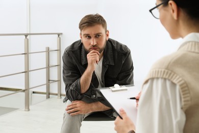Psychotherapist working with drug addicted young man indoors