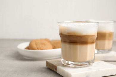 Glasses with delicious latte macchiato on white table, space for text