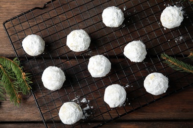 Christmas snowball cookies near fir tree branches on wooden table, flat lay