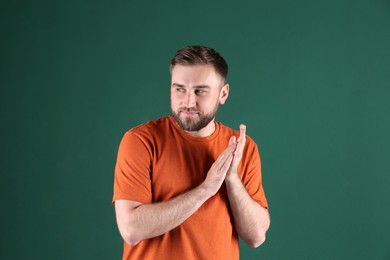 Greedy young man rubbing hands on green background