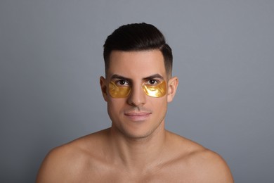 Man with golden under eye patches on grey background