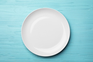 Stylish ceramic plate on wooden background, top view