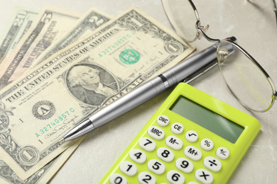 Calculator, pen, money and glasses on light table, closeup. Tax accounting
