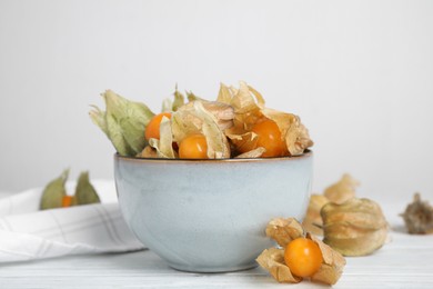 Ripe physalis fruits with dry husk on white wooden table
