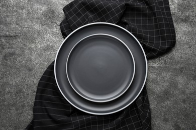 New dark plates and napkin on grey table, top view