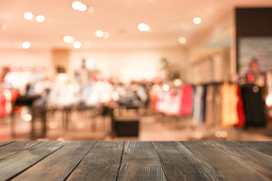Image of Empty wooden table and blurred view of store with modern clothes