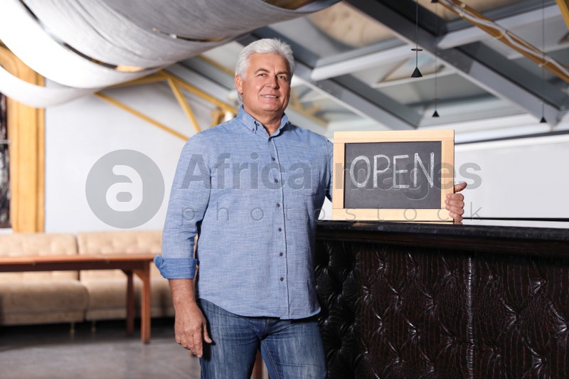 Senior business owner holding OPEN sign in his restaurant