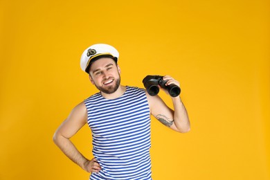 Happy sailor with binoculars on yellow background