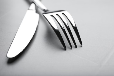 Shiny fork and knife on grey table, closeup