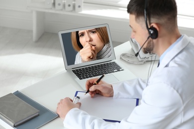 Image of Hotline service. Doctor consulting patient online via laptop indoors
