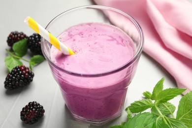 Delicious blackberry smoothie in glass and berries on white table, closeup