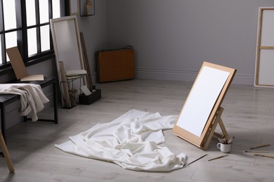 Photo of Stylish artist's studio interior with canvas, white fabric and brushes