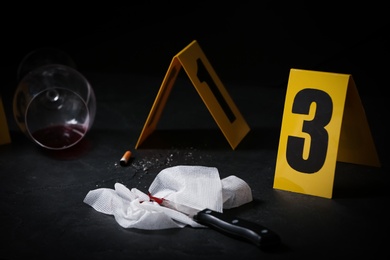 Knife and bloody napkin on black slate table at crime scene