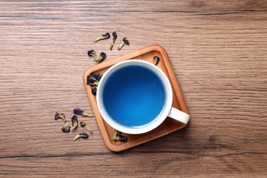 Organic blue Anchan in cup on wooden table, flat lay. Herbal tea