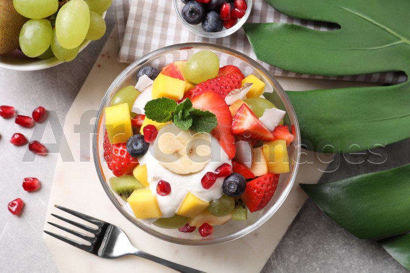 Delicious fruit salad on grey table, flat lay