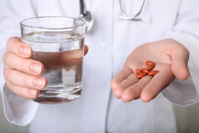 Doctor holding pills and glass of water, closeup. Anemia concept
