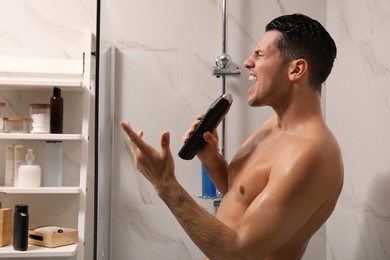 Man with bottle of gel singing in shower at home