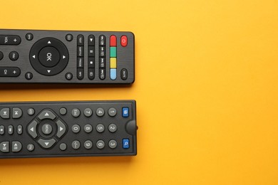 Remote controls on yellow background, flat lay. Space for text