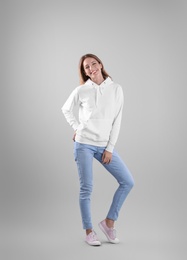 Photo of Full length portrait of woman in hoodie sweater on light background. Space for design