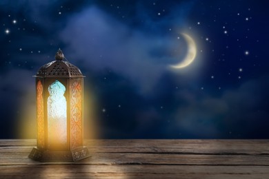 Beautiful decorative Arabic lantern on wooden table at night, space for text. Fanous as Ramadan symbol