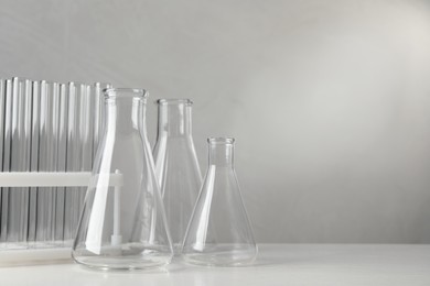 Set of laboratory glassware on white table against grey background, space for text