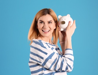 Woman with piggy bank on color background