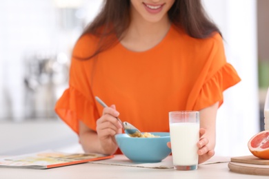 Photo of Beautiful young woman having breakfast and drinking milk at table