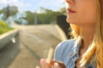 Photo of Woman smoking cigarette outdoors, closeup. Space for text