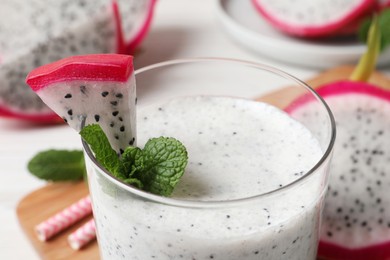 Photo of Glass of tasty pitahaya smoothie with fresh mint on table, closeup. Space for text