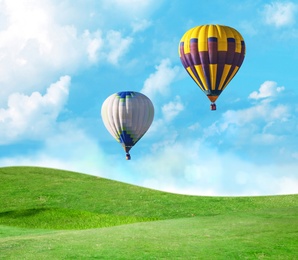 Fantastic dreams. Hot air balloons in blue sky with clouds over green meadow 
