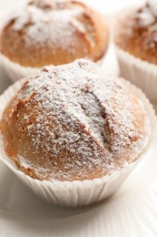 Tasty muffins powdered with sugar on plate, closeup