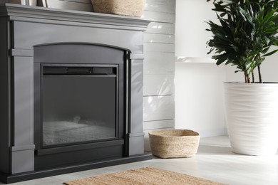 Modern electric fireplace near white wall indoors