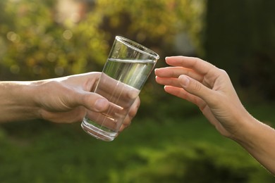 Man giving glass of fresh water to woman outdoors, closeup