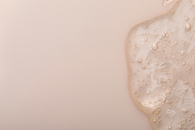 Pure transparent cosmetic gel on beige background, top view