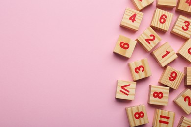 Photo of Wooden cubes with numbers and mathematical symbols on pink background, flat lay. Space for text