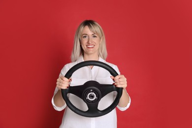 Happy woman with steering wheel on red background