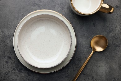 Stylish empty dishware and spoon on grey table, flat lay