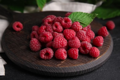 Wooden board with fresh ripe raspberries on table, closeup