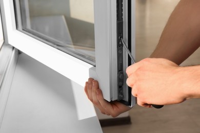 Worker adjusting installed window with screwdriver indoors, closeup
