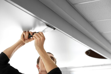 Repairman installing white stretch ceiling in room, closeup