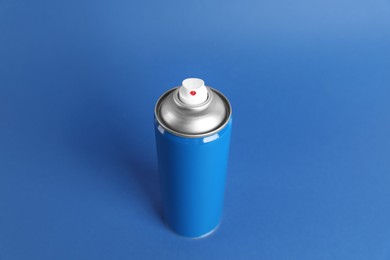 Can of spray paint on blue background, above view