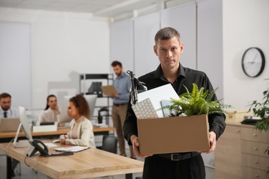 Upset dismissed man carrying box with stuff in office, space for text