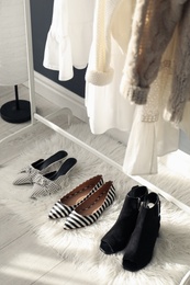 Photo of Faux fur rug with stylish women's shoes indoors. Interior design