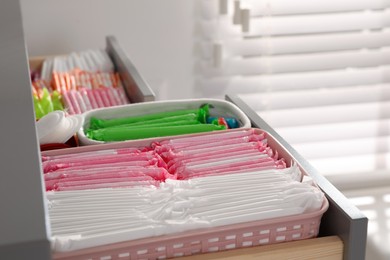 Open cabinet drawer with menstrual pads, tampons and pantyliners indoors, closeup