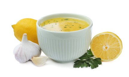 Photo of Bowl with lemon sauce and ingredients on white background. Delicious salad dressing