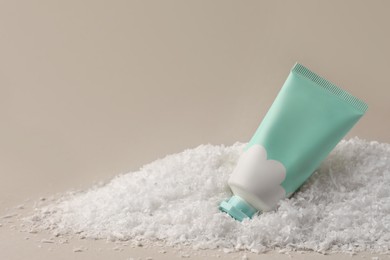Photo of Winter skin care. Hand cream on artificial snow against light grey background, space for text